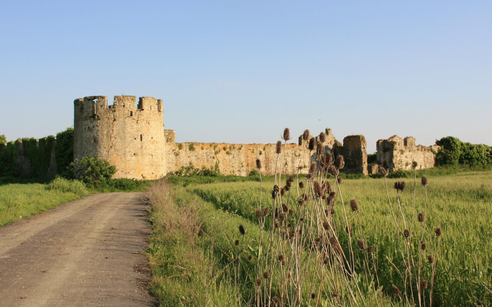 A rectangular walled fortress with a round corner tower, standing in open farmland
