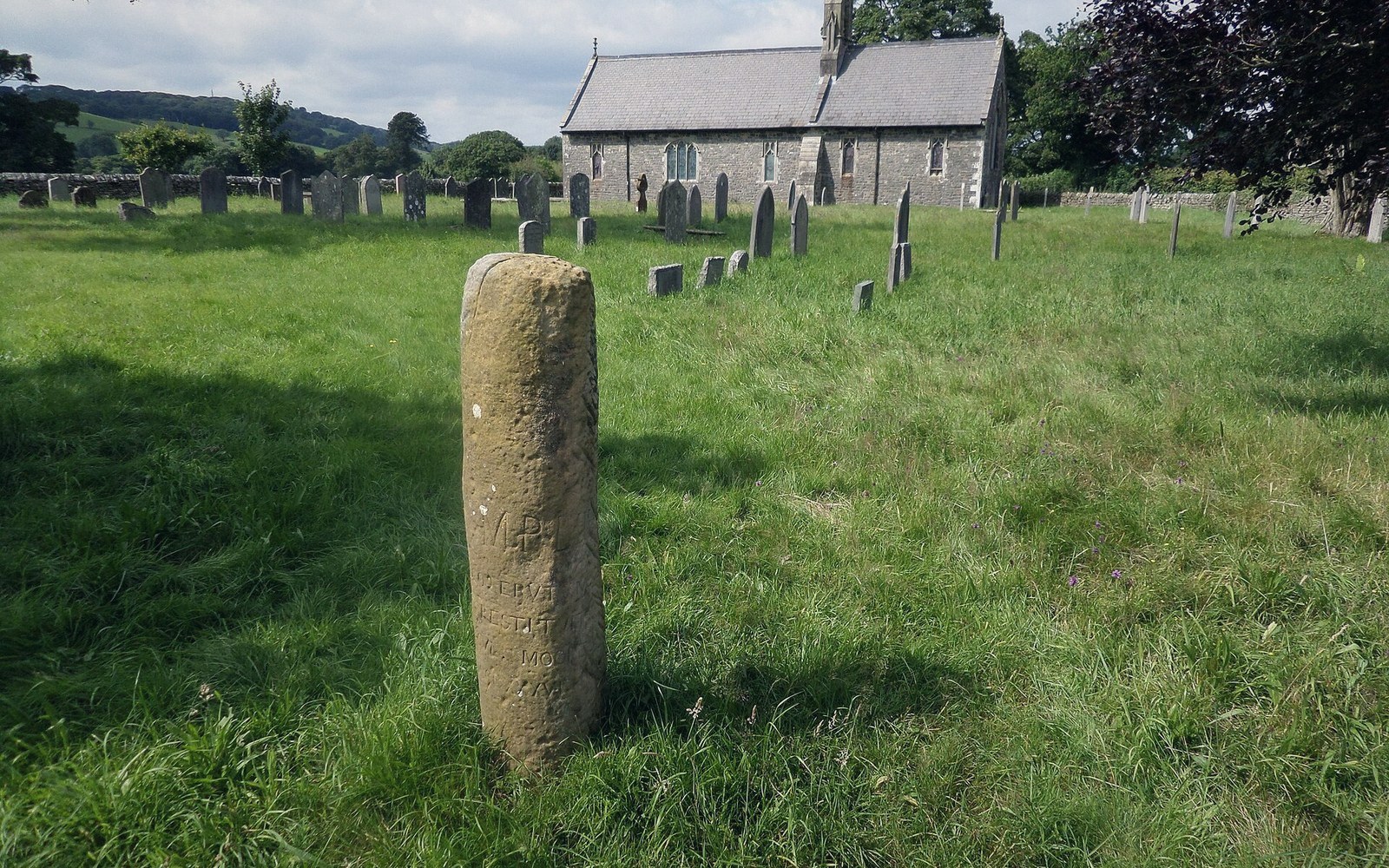 A weathered Roman milestone standing in a churchyard